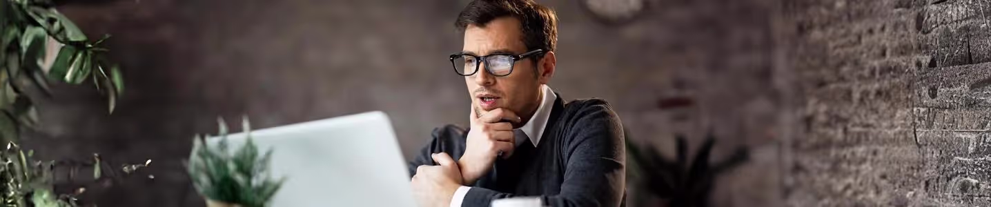 Um jovem está pesquisando em seu notebook sobre a quantidade ideal de megabits de internet, buscando informações para garantir uma conexão adequada às suas necessidades online.