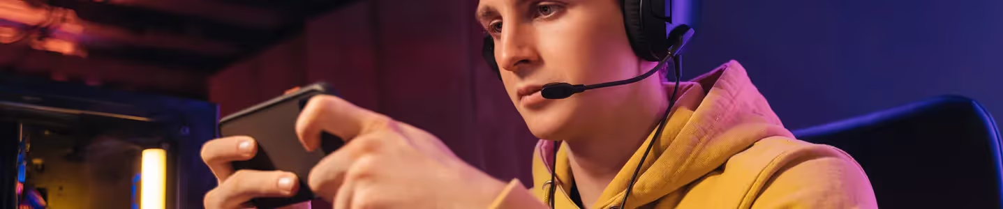 Com entusiasmo, um jovem rapaz utiliza a nova tecnologia 5G para desfrutar de uma excelente conexão com a internet, permitindo-lhe jogar tranquilamente em seu celular, sem preocupações com a velocidade ou latência.