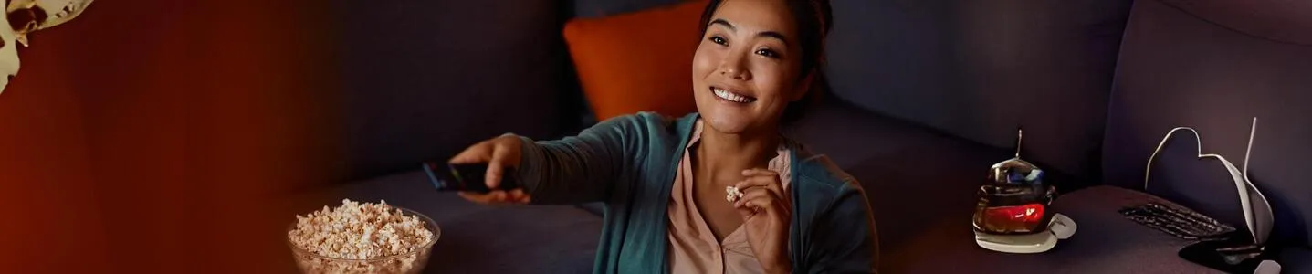 Uma jovem mulher desfruta ao máximo de sua TV 4K, vivenciando uma experiência cinematográfica imersiva em casa.