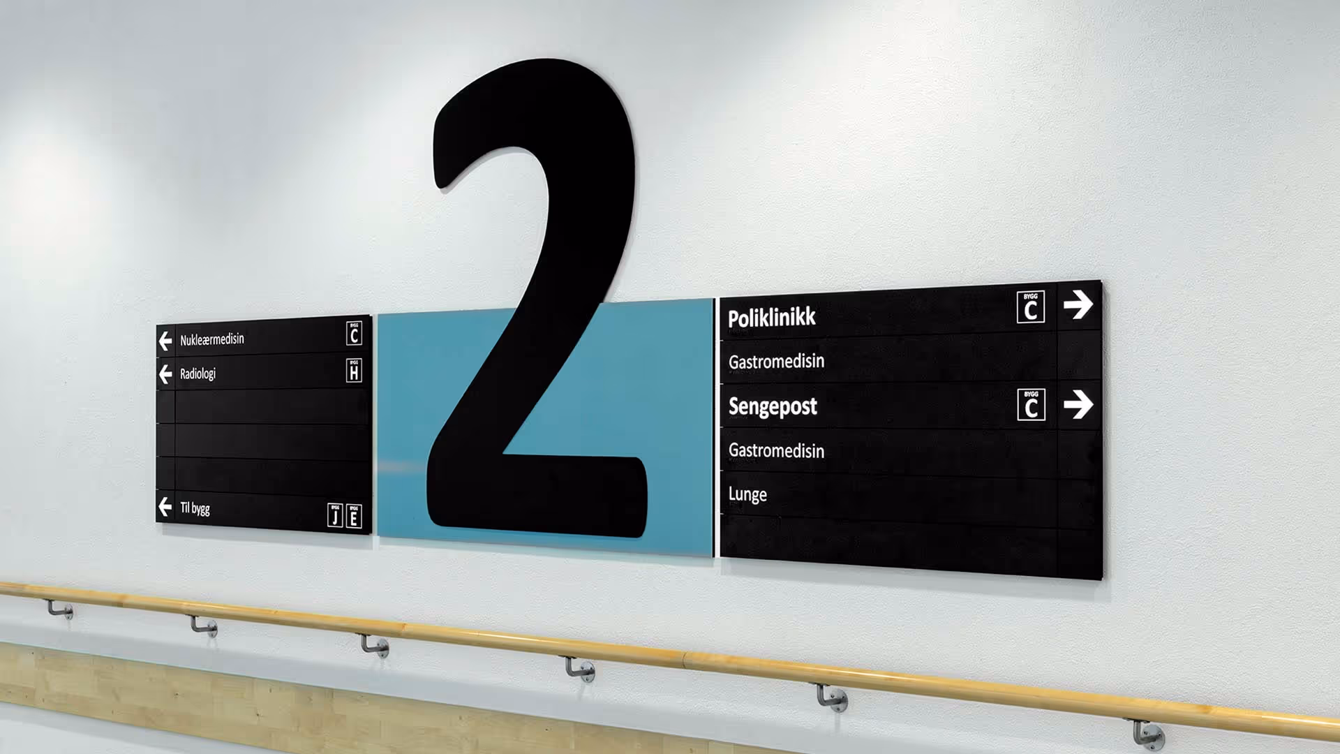 Skilting i en sykehusgang med nummer 2 og piler som viser retninger til Nukleærmedisin, Radiologi, Poliklinikk, Sengepost, og Lunge.