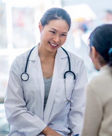 a medical worker in a lab coat talking to a patient