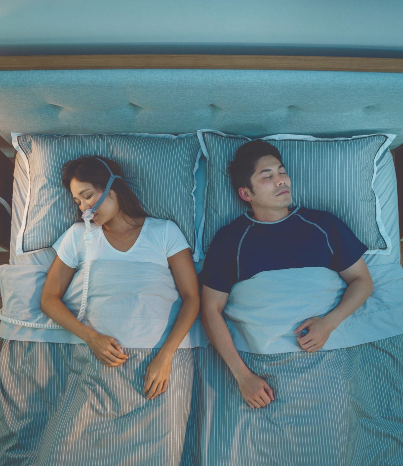 Two adults, woman and man sleeping, she wares air mask