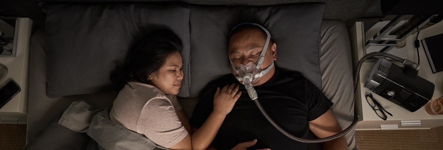 Woman and a man sleeping, man with air mask