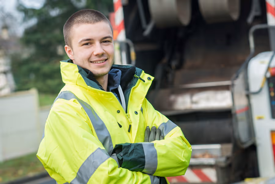White Mercedes refuse truck parked inside a warehouse with overhead lighting.
