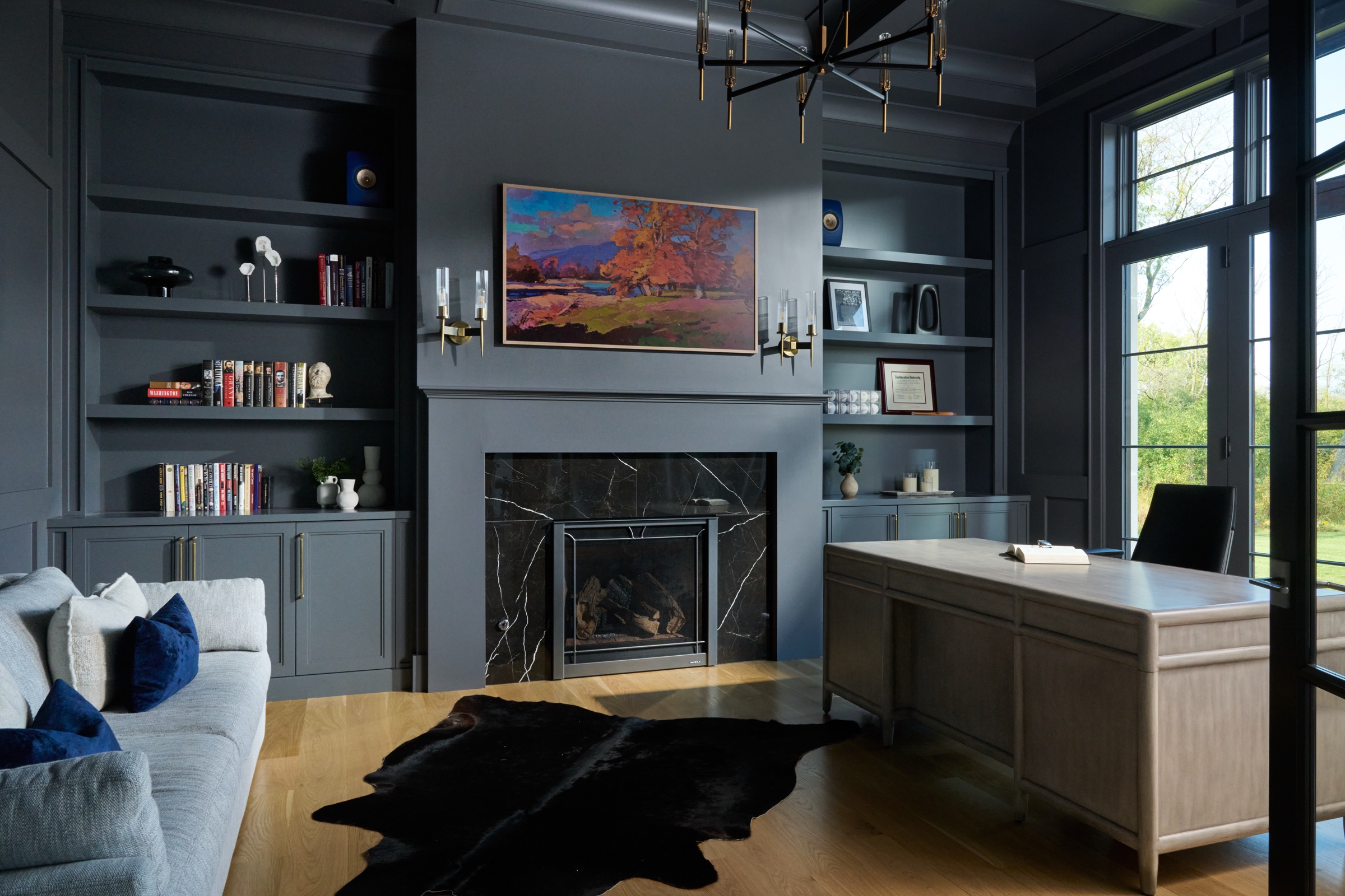 The paneled study features charcoal built-ins, a black marble fireplace, and a private desk overlooking the estate.
