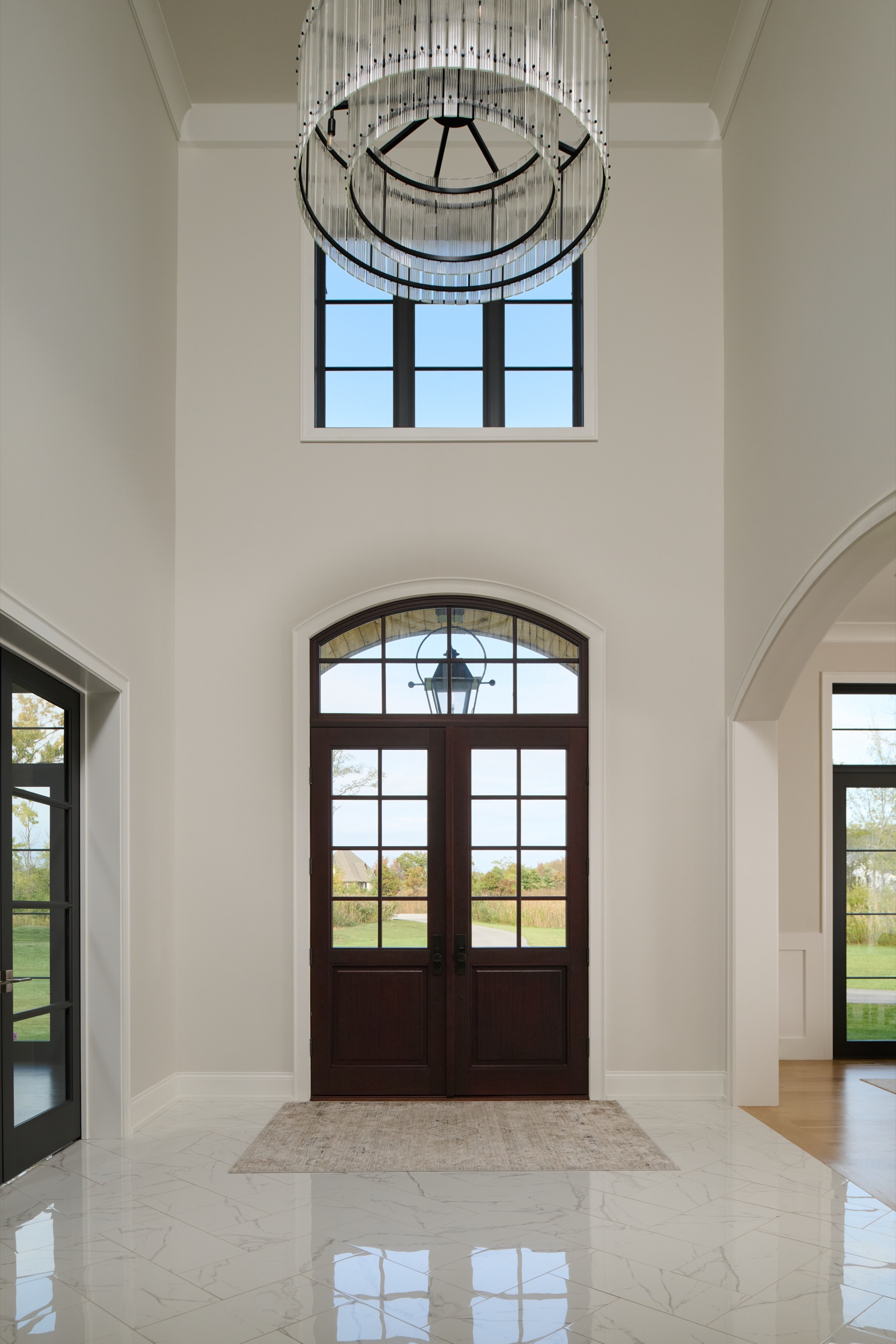 The vaulted two-story grand foyer with a crystal drum chandelier and marble floor inside the Mettawa estate.