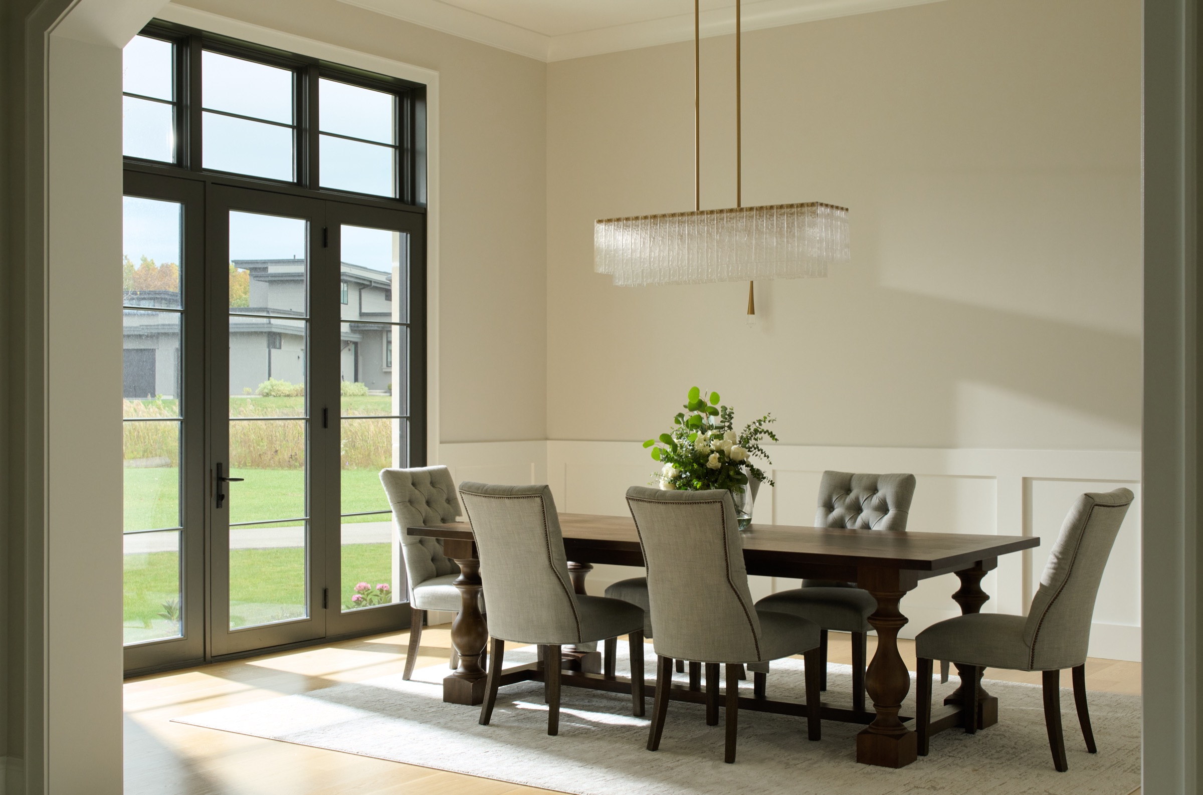 An alternate view of the dining room, filled with natural light from black-framed French doors opening to the yard.
