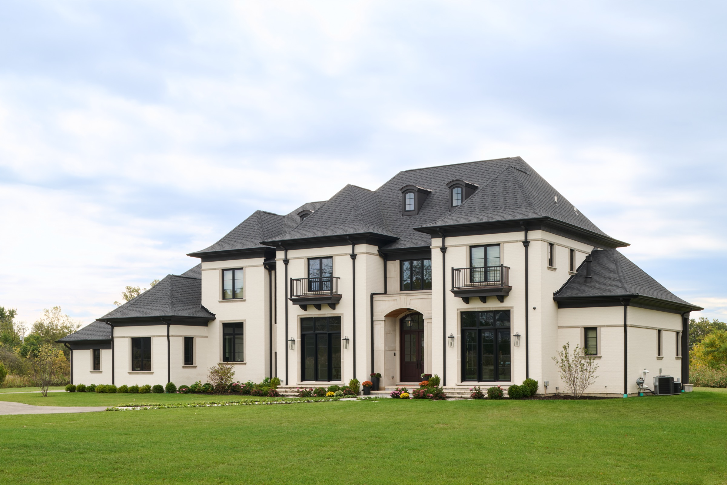 A wide view of the full-masonry exterior and manicured lawn of the Georgian custom estate in Mettawa, IL.