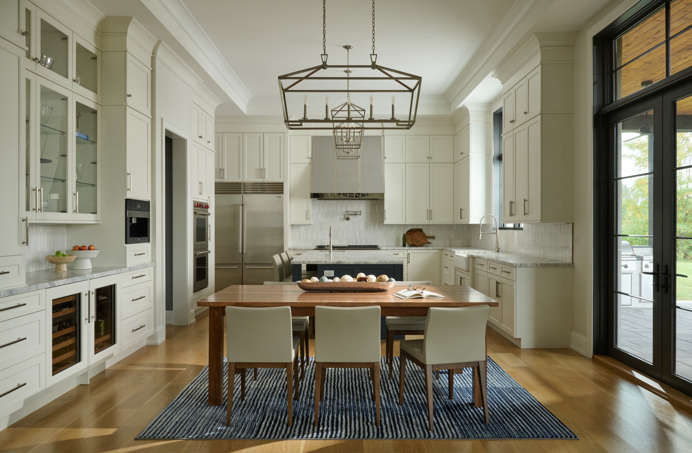 The custom kitchen with white cabinetry, marble countertops, a navy island, and French doors leading to the covered patio.