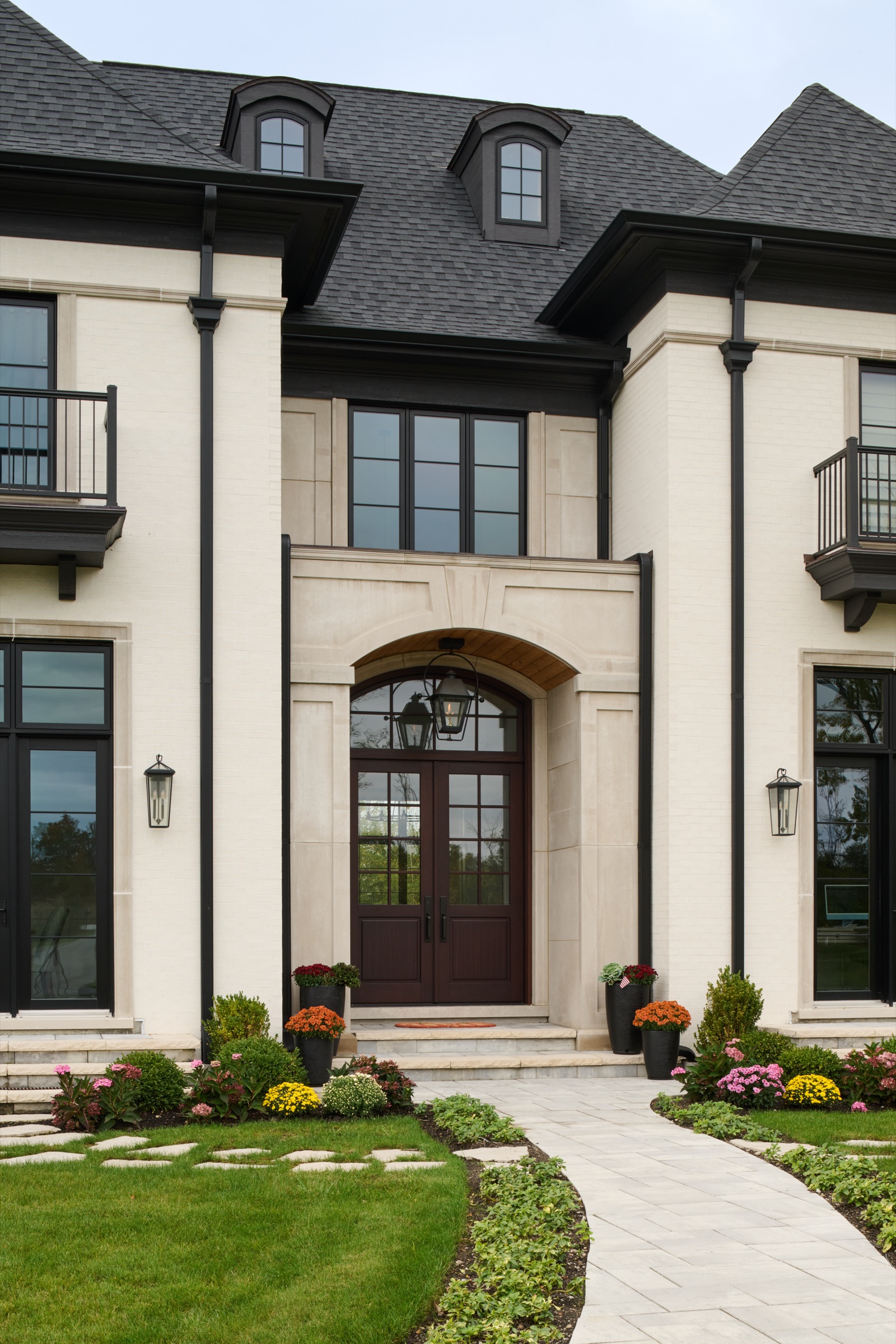 The centered front entry with an arched limestone surround and mahogany double doors on the Mettawa custom home.