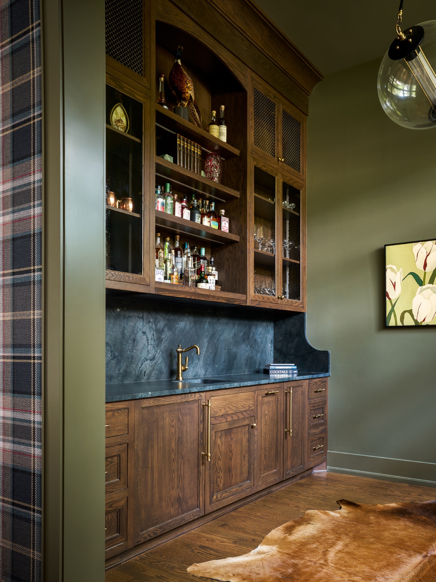 Custom-designed cabinetry within a speakeasy adjacent to the billiards room, featuring a marble countertop and backsplash, a beverage fridge and freezer, a full-sized dishwasher, and a sink—the perfect entertainment setting.