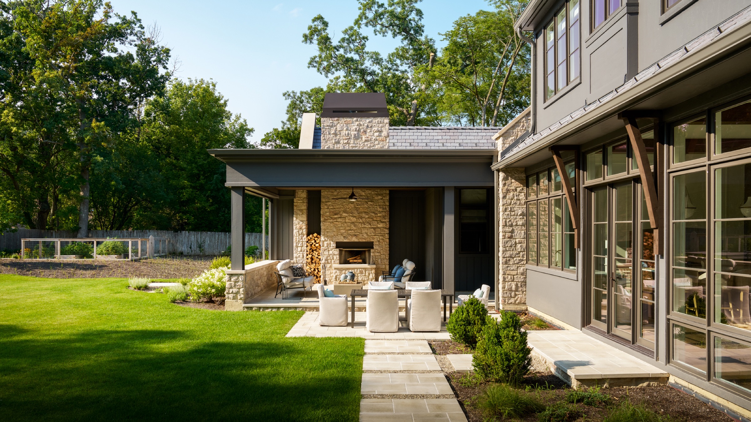 The three-season room/sunset porch, featuring an outdoor wood-burning fireplace and an outdoor seating and dining area. An exterior courtyard strongly connects the three-season room to the billiards room on the opposite wing of the home.