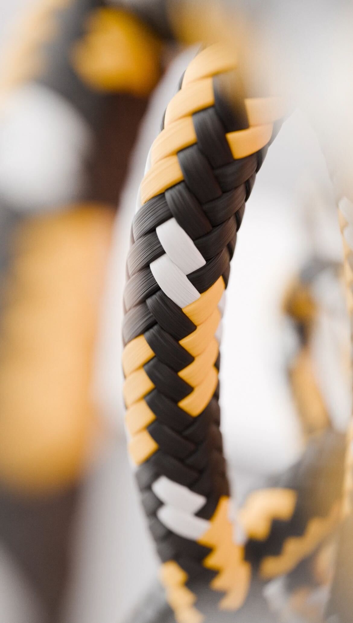 Close-up of a braided handle wrapped in black, yellow, and white synthetic material.
