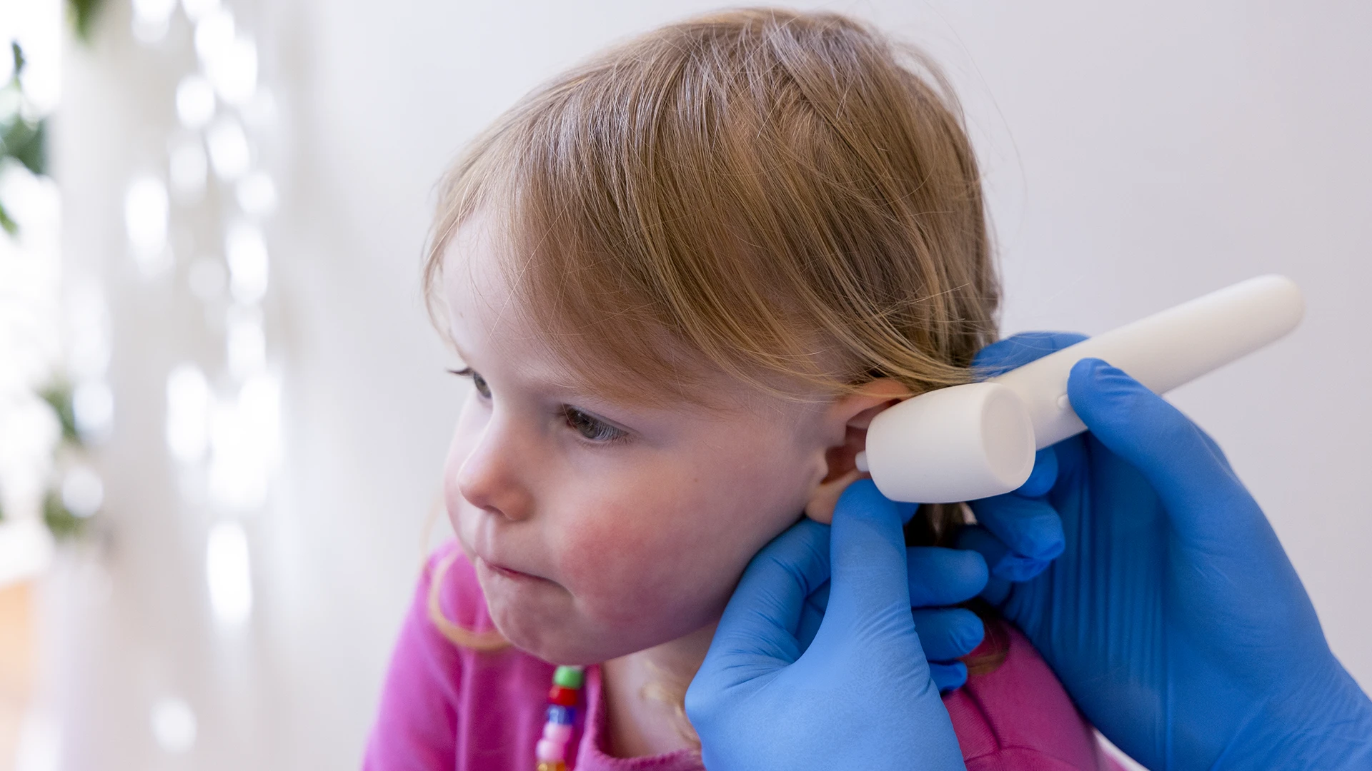 Doctor using the OTO K1 pediatric otoscope during an ear examination with a young patient.