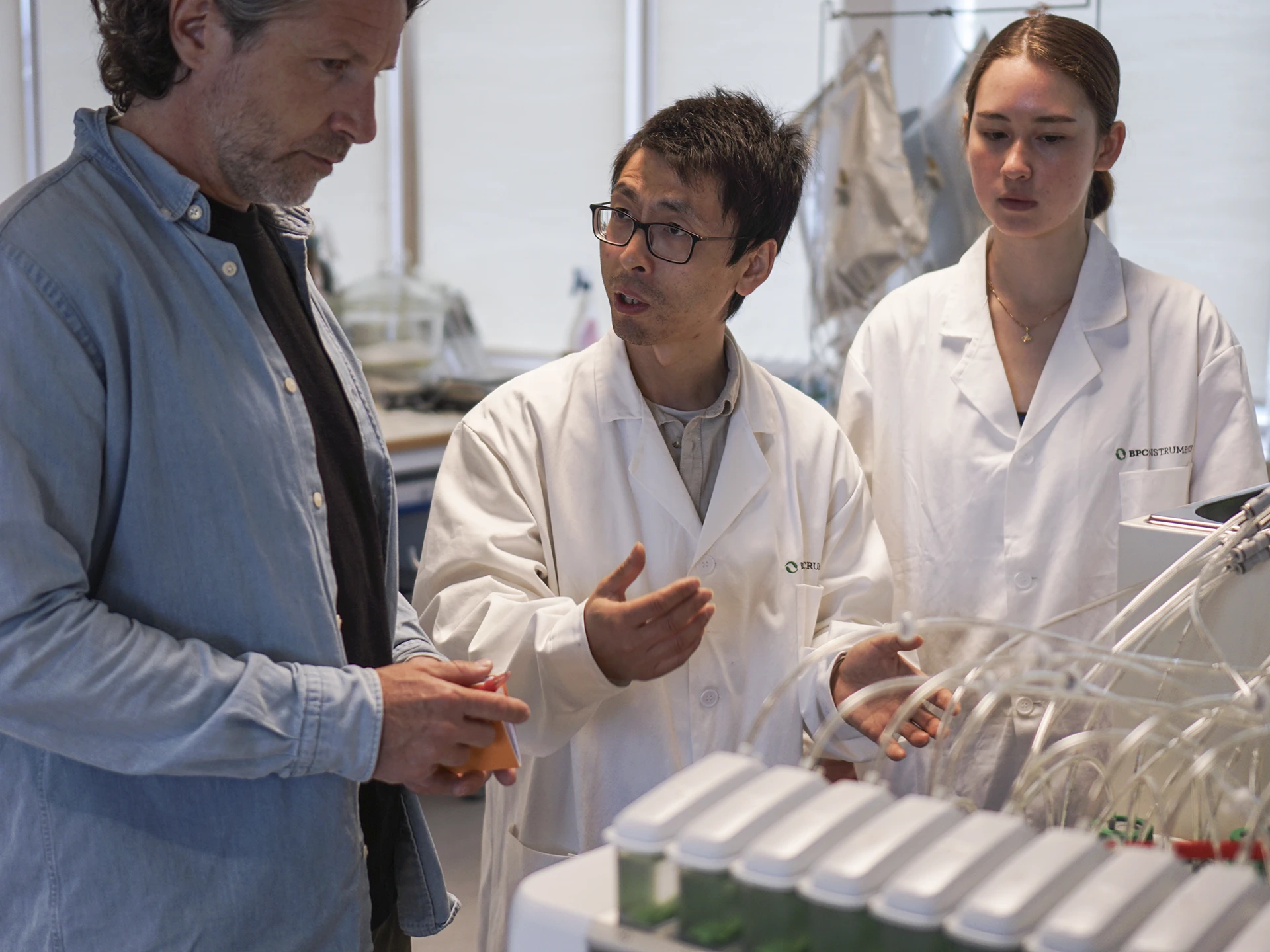 Designer discussing lab workflows with bioanalysts at BPC, with instruments visible in the background.
