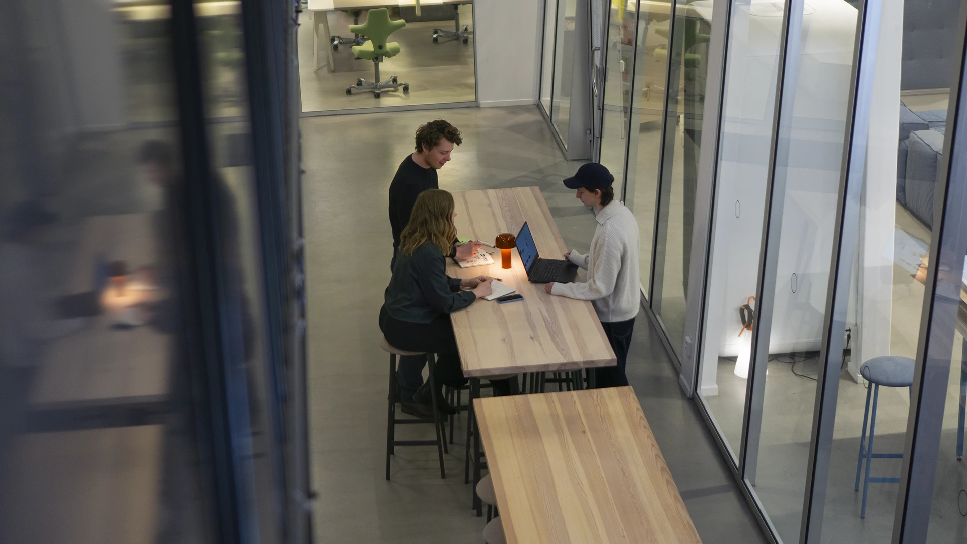 Team collaborating around a long table in a creative workshop setting, viewed from above.