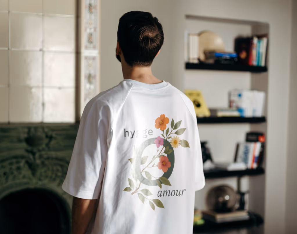 Ein Mann trägt ein weißes T-Shirt mit Blumen und den Worten „hygge amour“ auf dem Rücken.