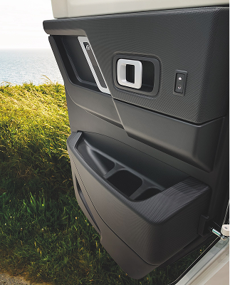 Open car door interior showing black textured panel with handle and storage compartment.