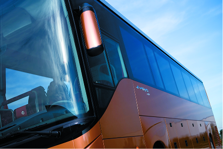 Close-up angle of a modern bronze-colored coach bus under a bright blue sky.