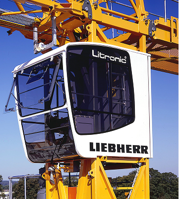 Close-up of a white Liebherr Litronic crane operator cabin against a clear blue sky.
