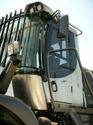 Close-up of a heavy-duty vehicle cabin with protective bars and side mirror.
