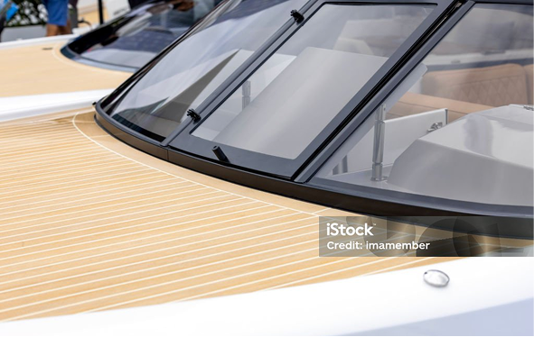 Close-up of a yacht's wooden deck and glass windshield with wipers on a sunny day.