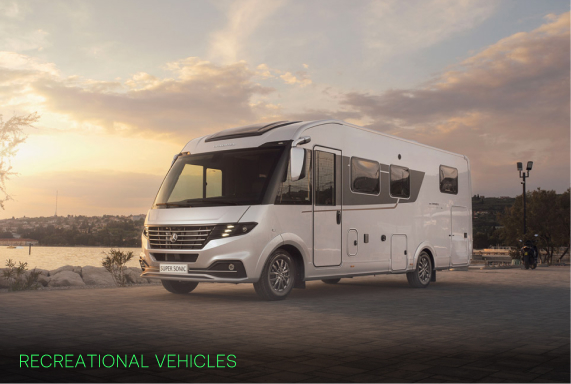 White luxury recreational vehicle parked near a waterfront at sunset with a cloudy sky.