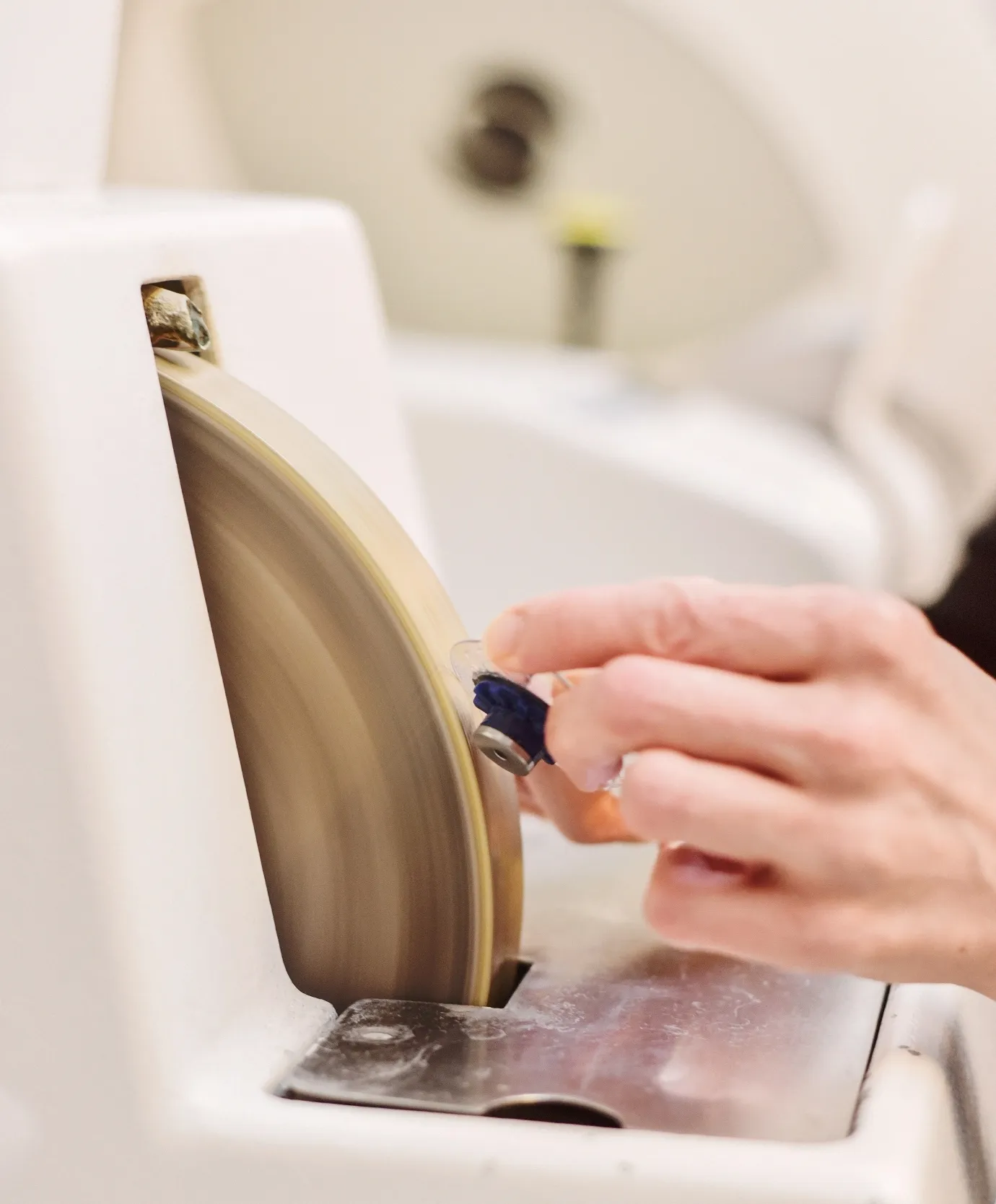 Hand poliert Brillenglas an einem rotierenden Schleifscheibenrad.