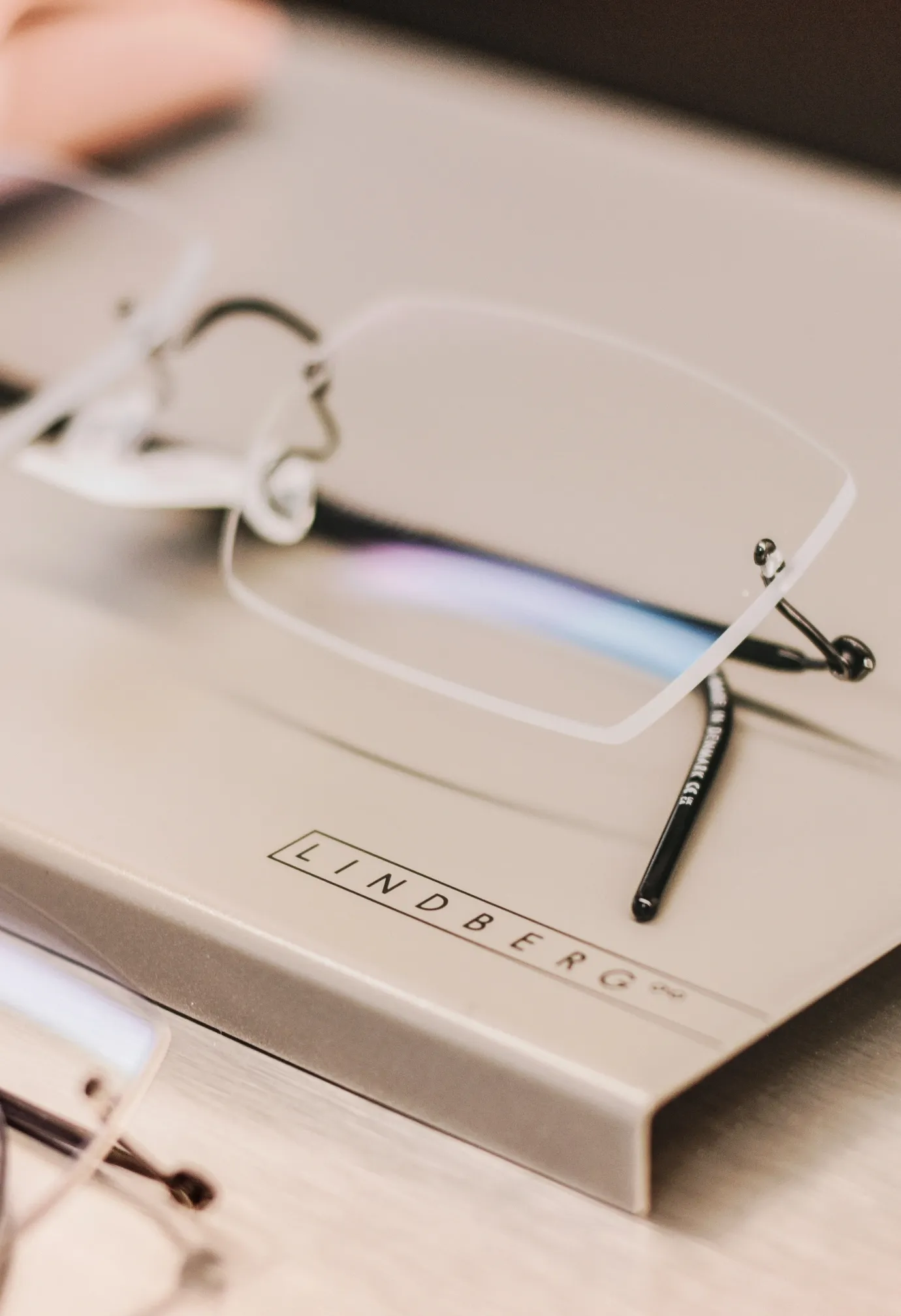 Brillengestell mit randlosen Gläsern liegt auf einer Box mit der Aufschrift "LINDBERG".