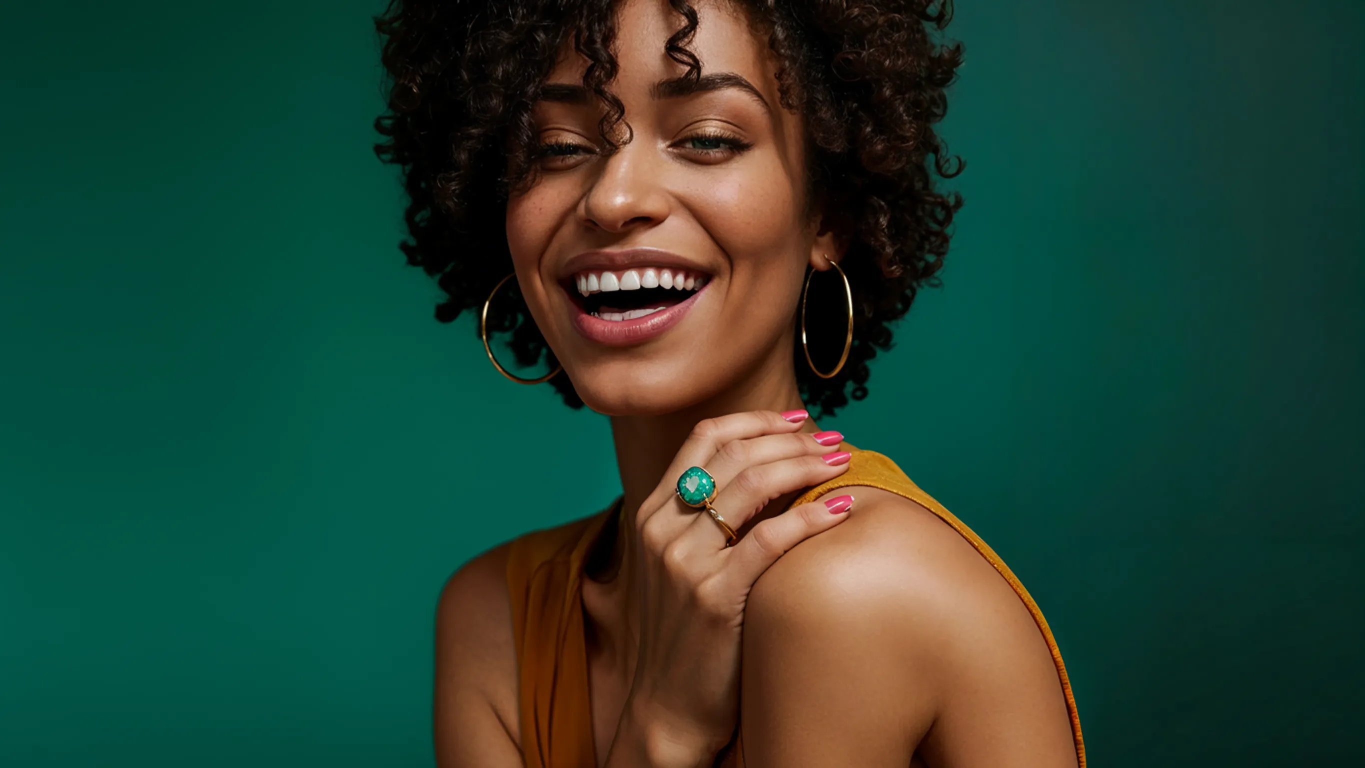 A woman with curly hair smiling and wearing earrings.