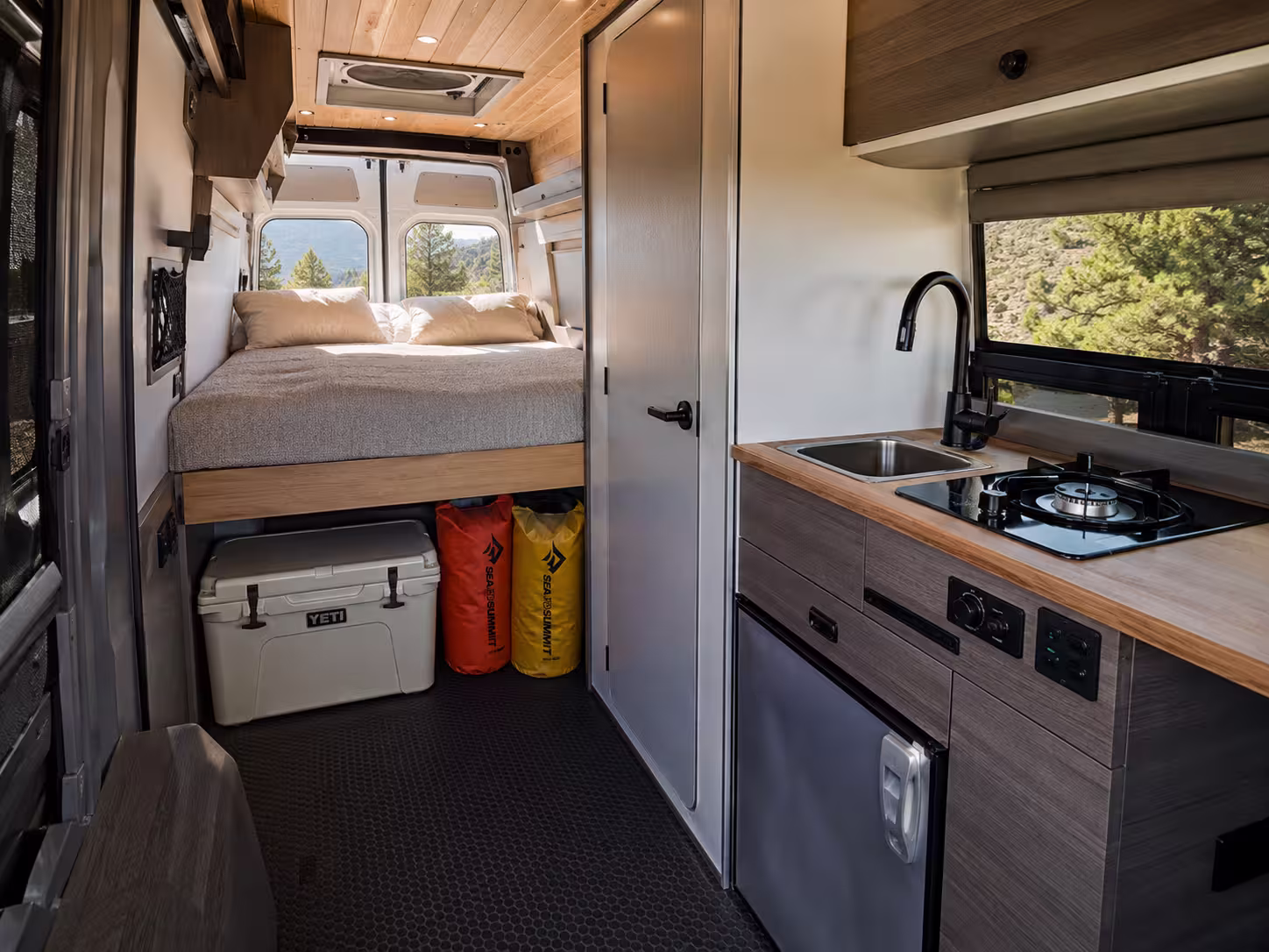 Inside a Class B camper van rental showing bed, galley, and storage