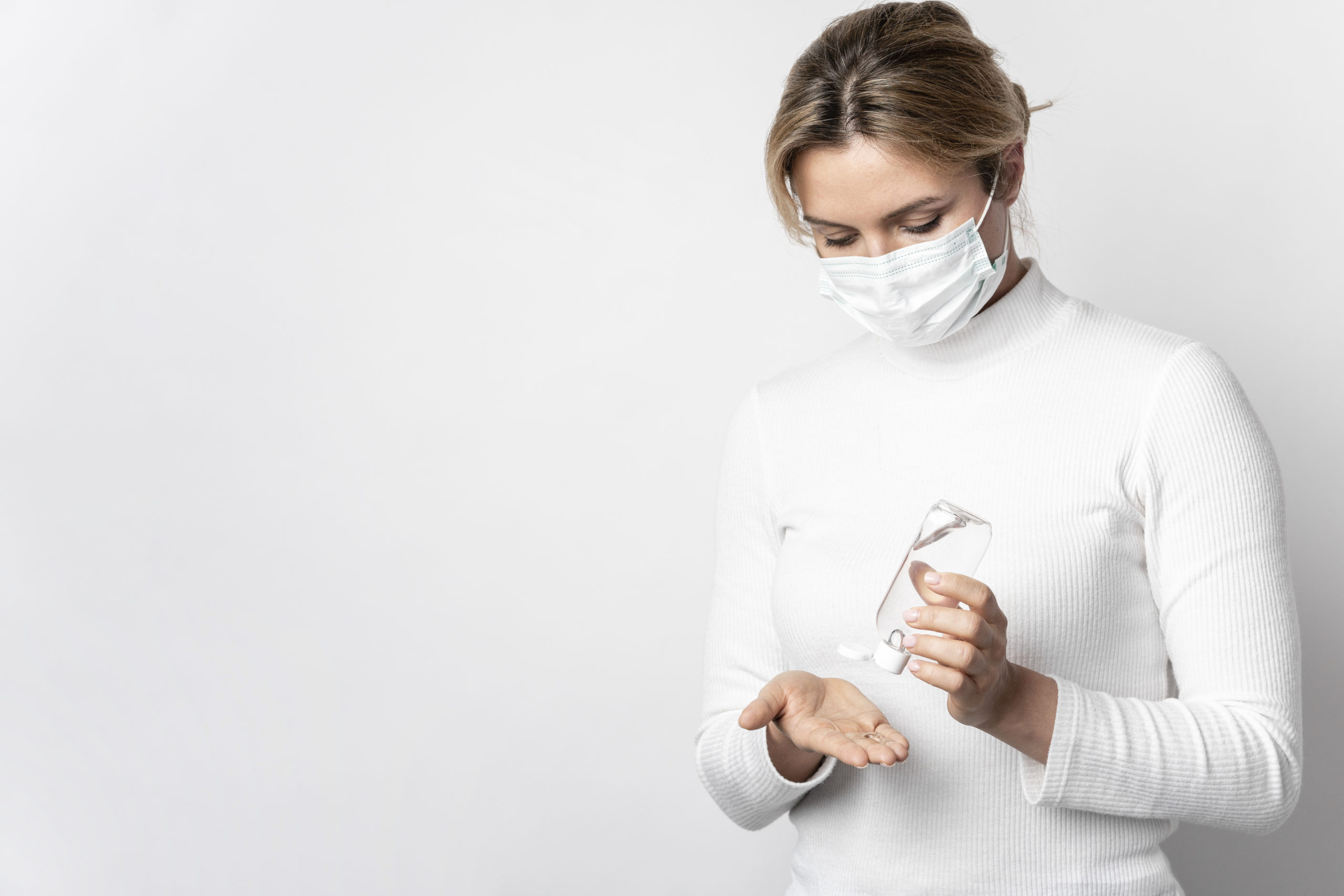 Woman wearing mask and using hand sanitizer