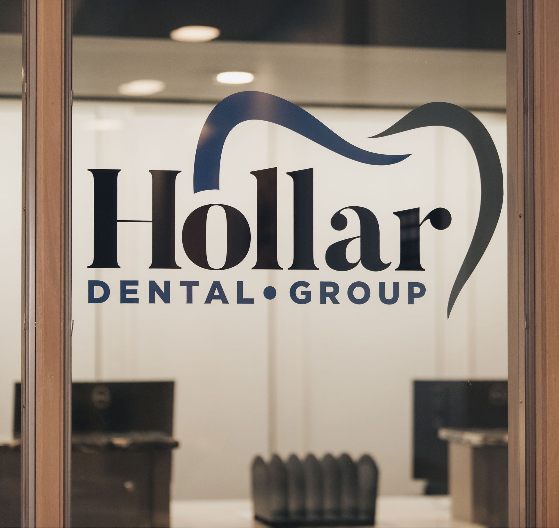 "Hollar Dental Group" logo on a glass door with a stylized tooth outline.
