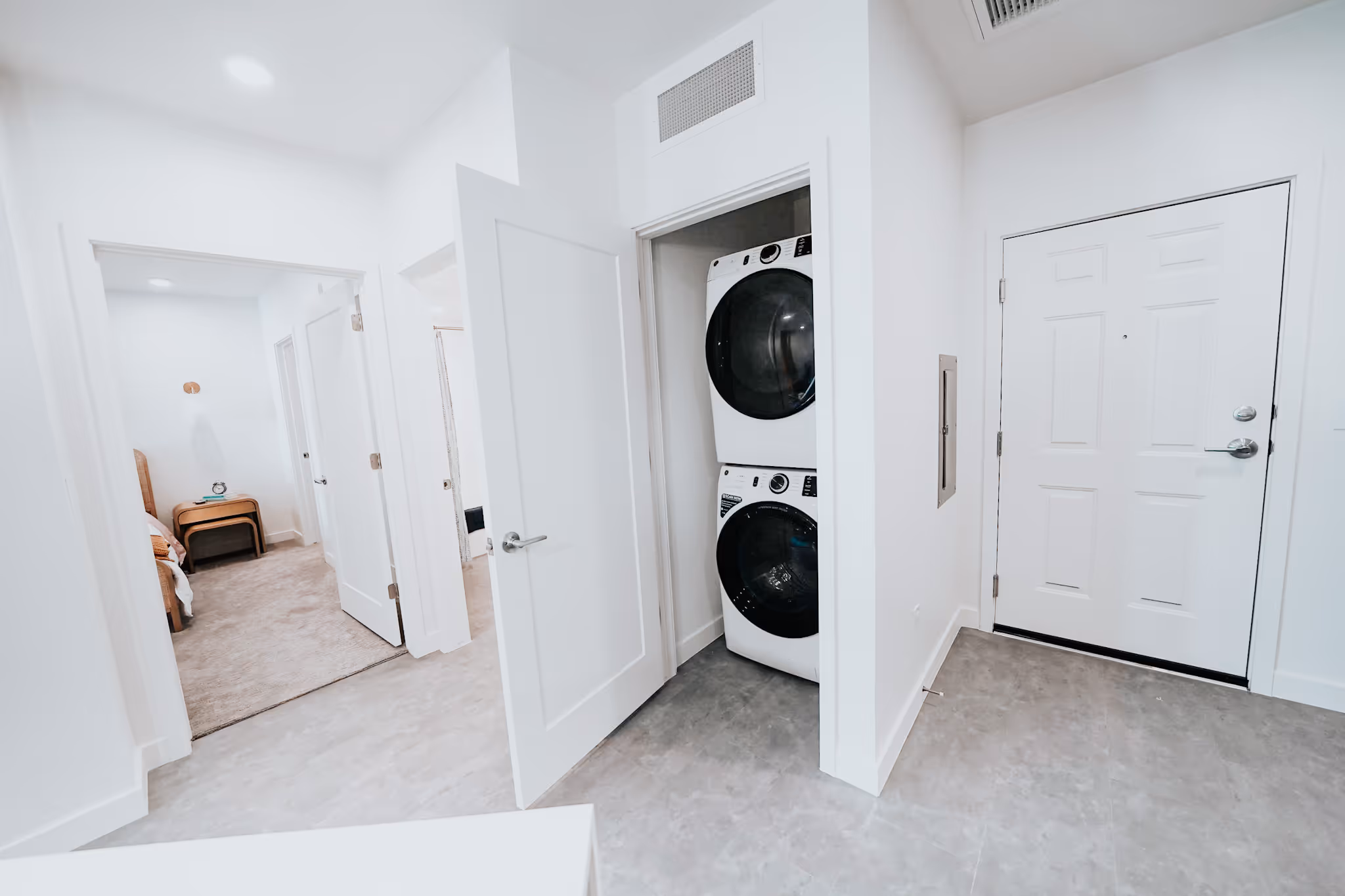 hallway with laundry room, entry door and view of bedroom