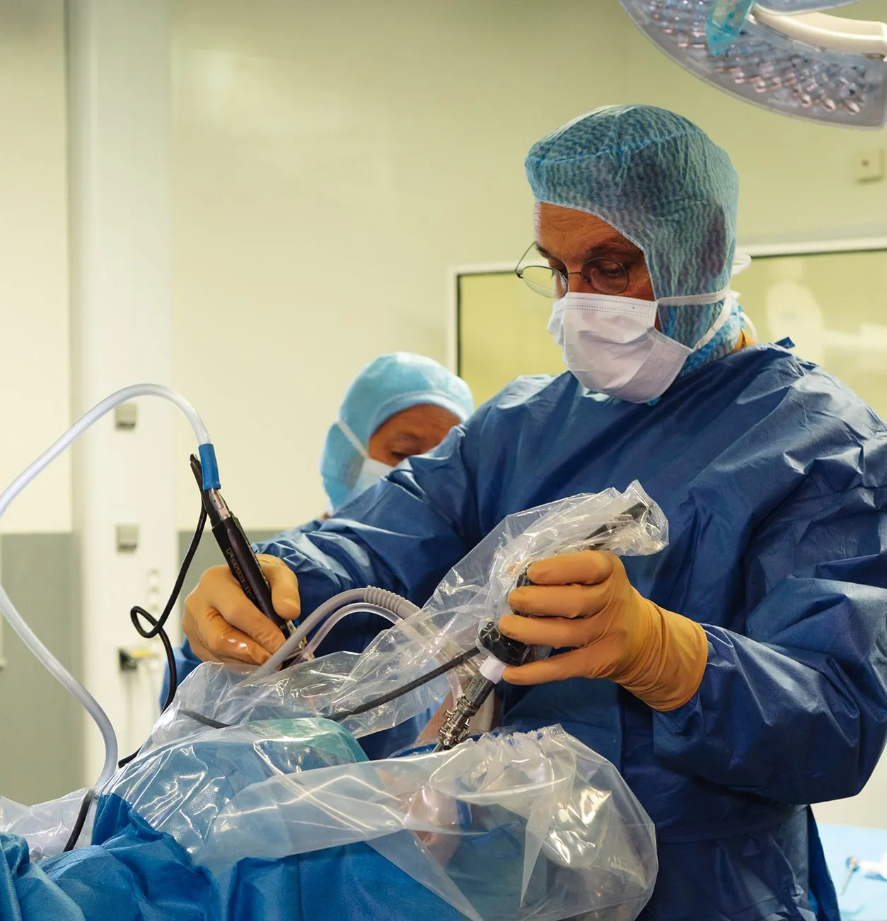 Chirurgien portant une tenue stérile opérant avec des instruments médicaux lors d'une intervention en salle d'opération.