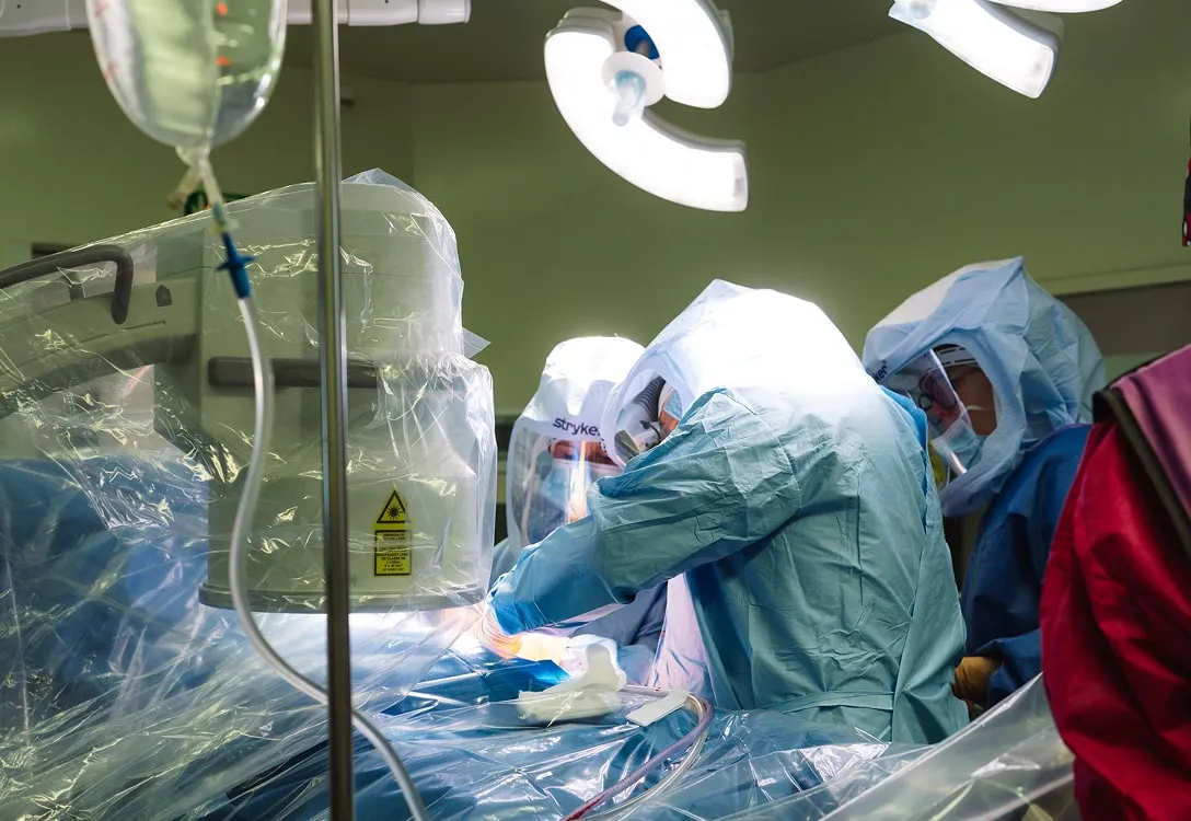 Chirurgiens en tenue de protection réalisant une opération assistée par un robot médical dans une salle d'opération.