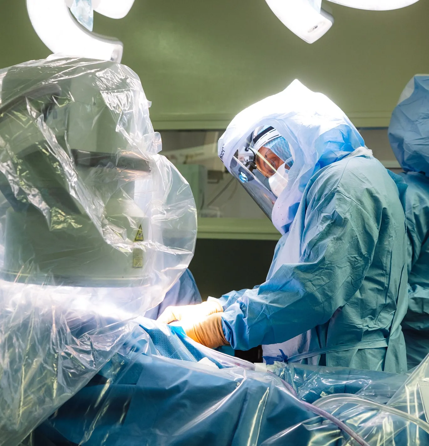 Chirurgien en tenue stérile avec appareil de protection effectuant une opération dans une salle d'opération moderne.