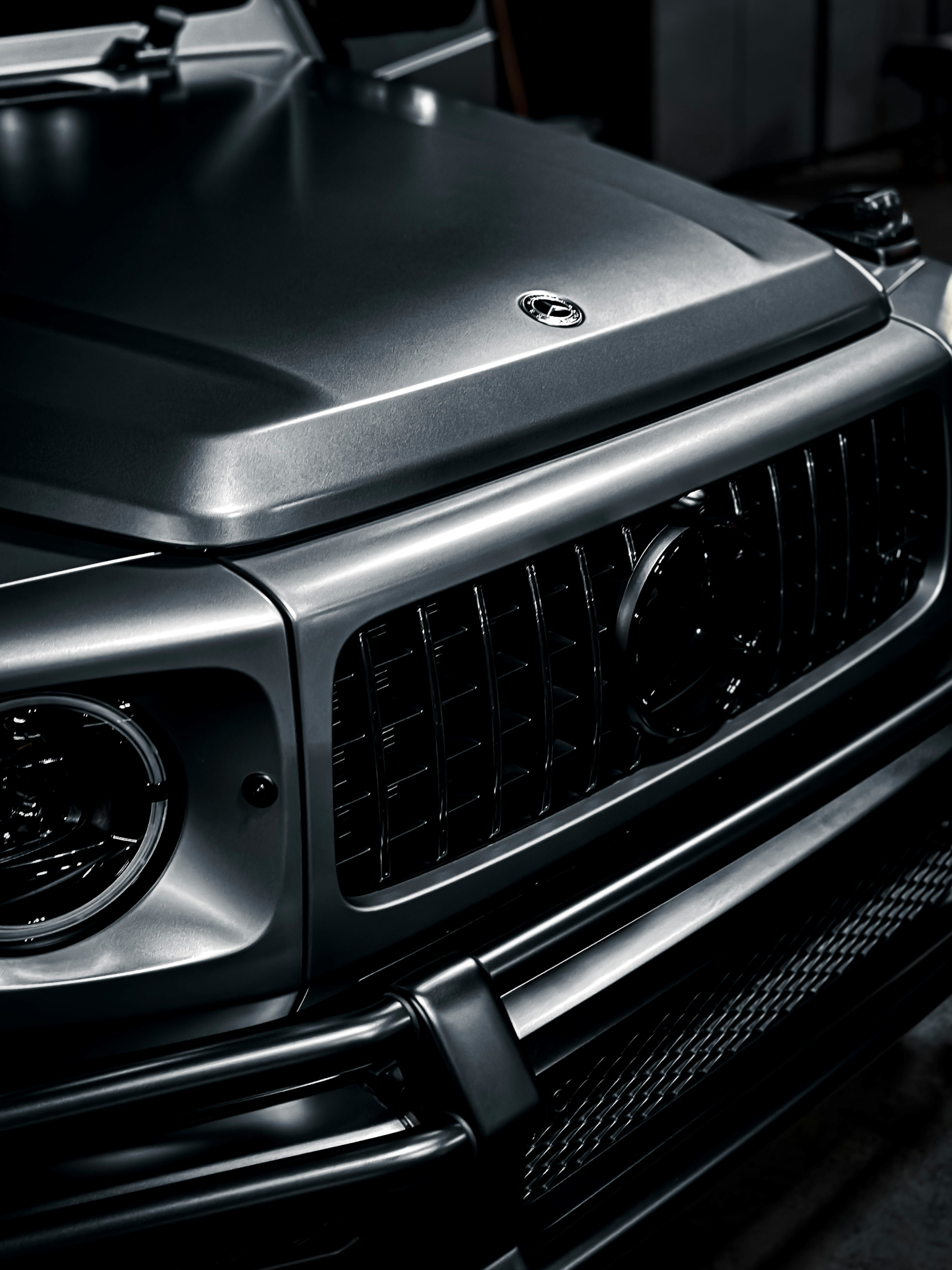 Gray Mercedes-Benz G-Class SUV parked on a brick driveway near trees.