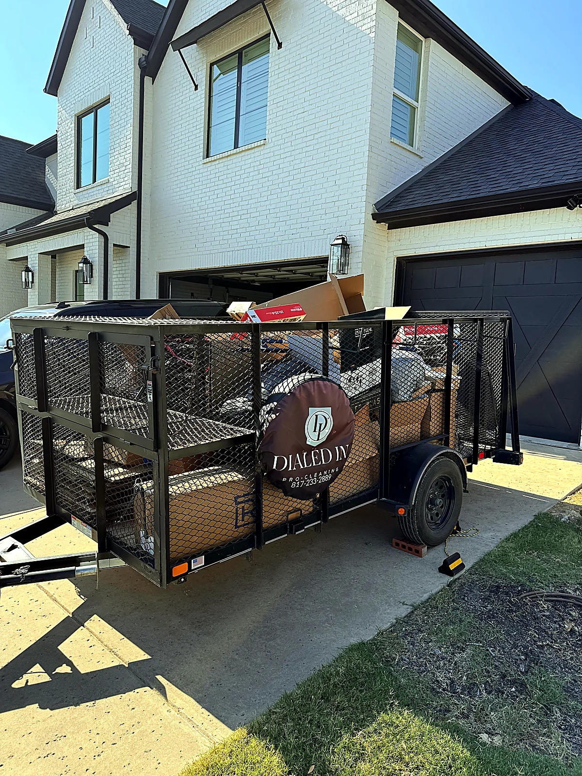Dialed In Pro Cleaning self-load junk removal trailer parked in a driveway at a Dallas-Fort Worth home