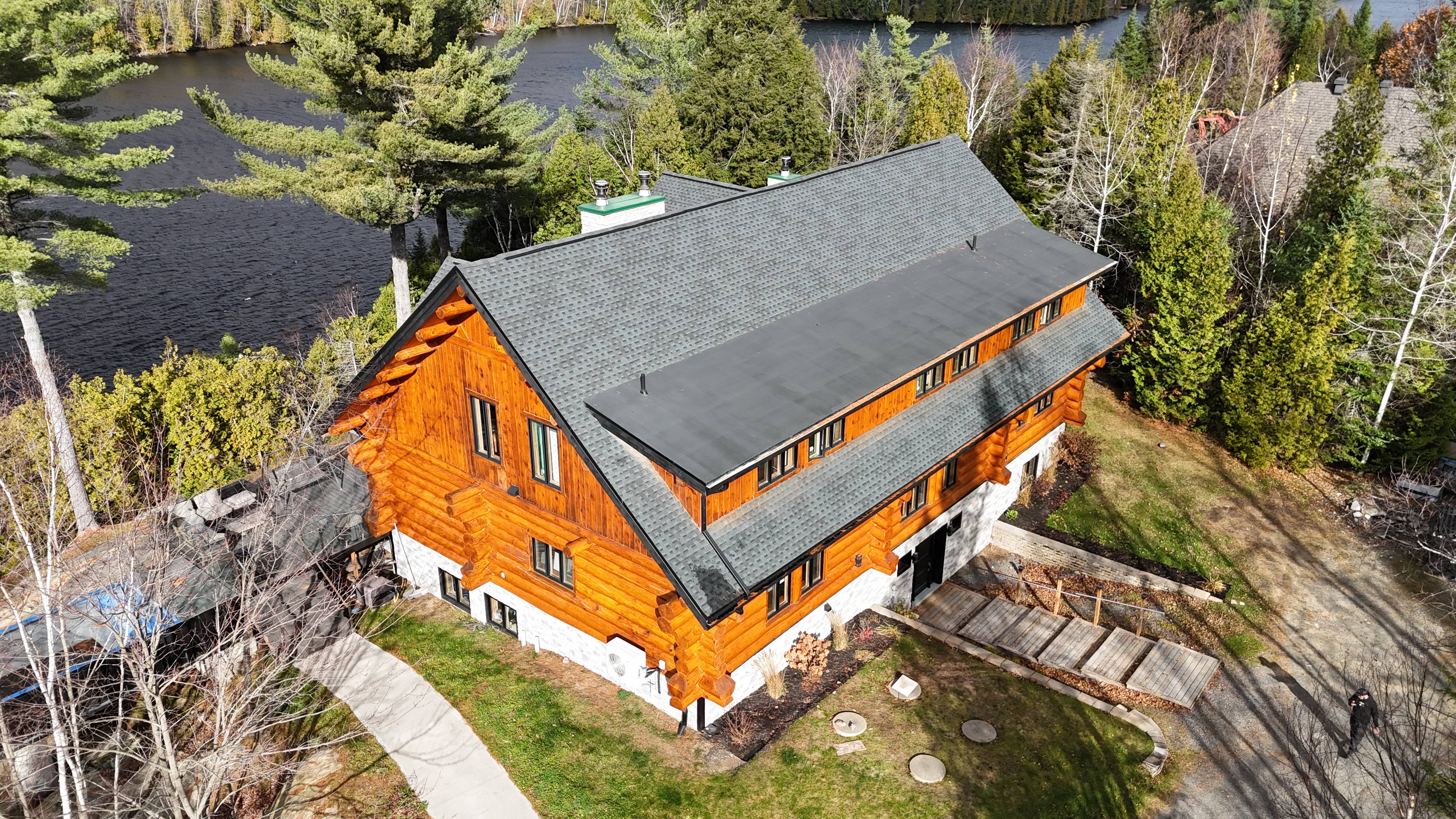 Vue aérienne du chalet en bois rond du Domaine de la Pitoune après restauration