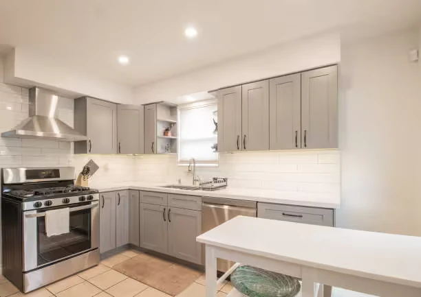 Modern small kitchen with gray cabinets, stainless steel appliances, and white countertops.