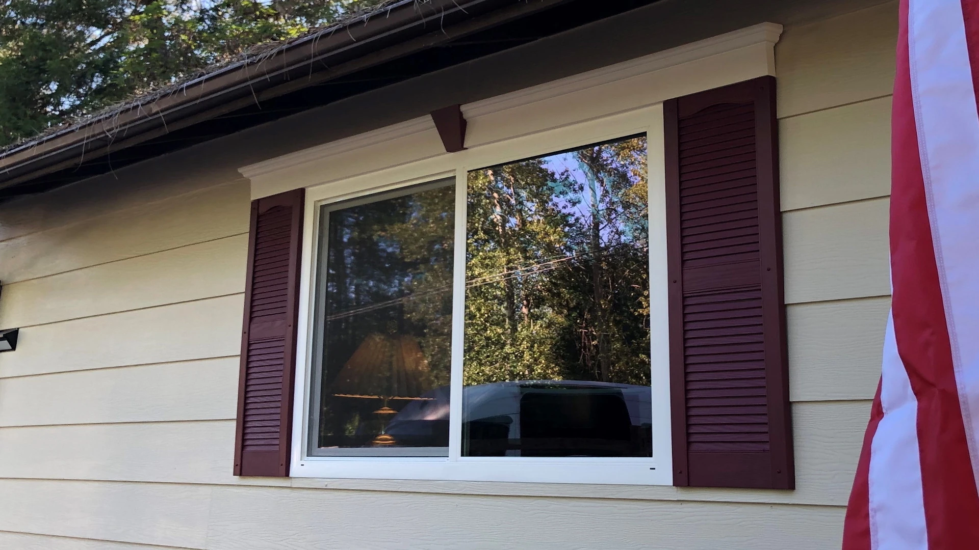 Modern bathroom with gray tiled bathtub and shower, white toilet with rolled towel, and vanity with sink and green leaf in vase.