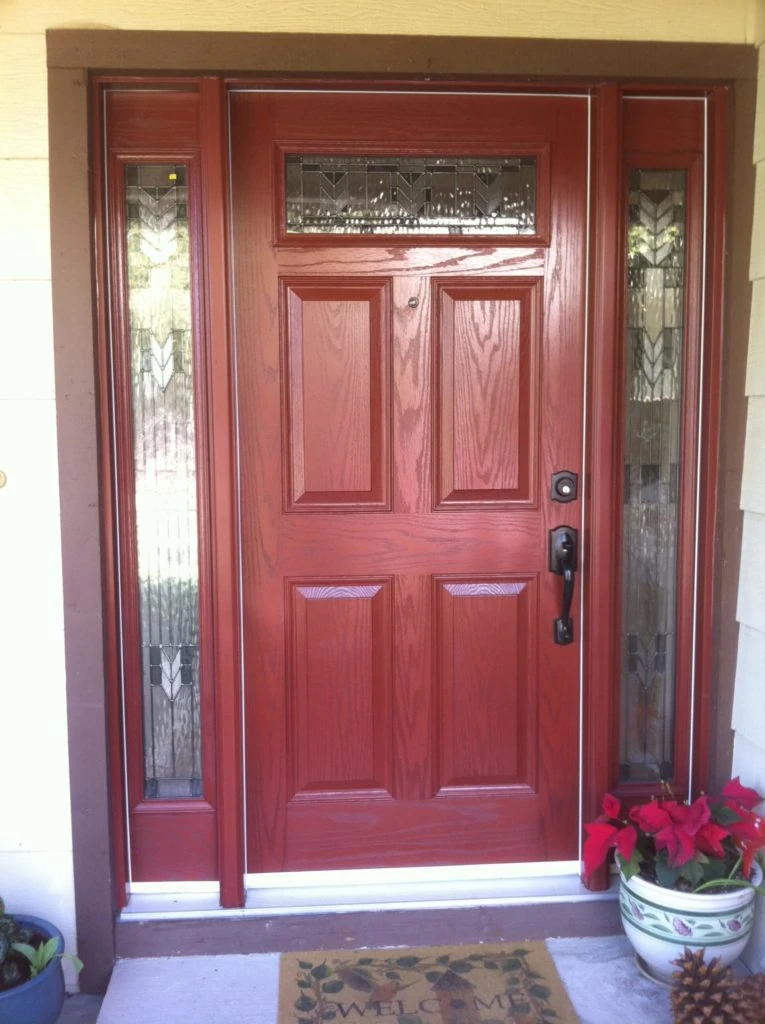 Modern kitchen with light gray cabinetry, white countertops, black fixtures, three wooden stools at island, and a window overlooking greenery.