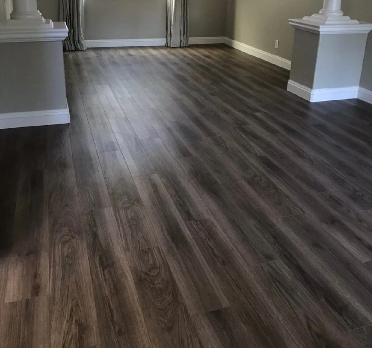 Modern bathroom with gray tiled bathtub and shower, white toilet with rolled towel, and vanity with sink and green leaf in vase.