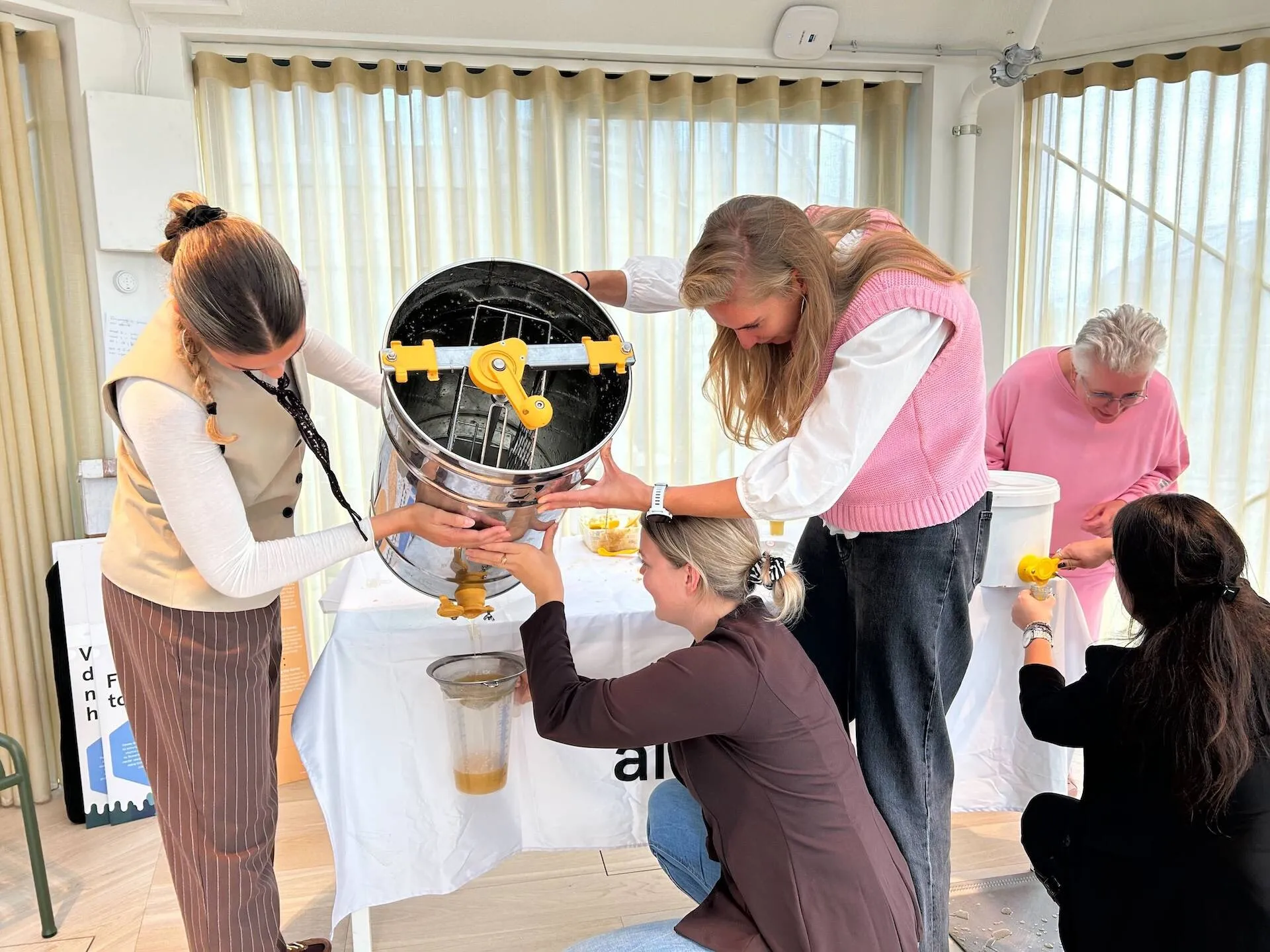 Women operating a honey extractor during an Alvéole beekeeping workshop event in the Netherlands
