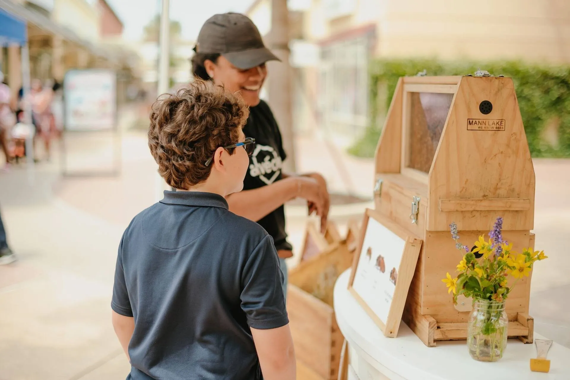 Alvéole educator and a child looking at an observation hive display at a Tanger Outlets activation event