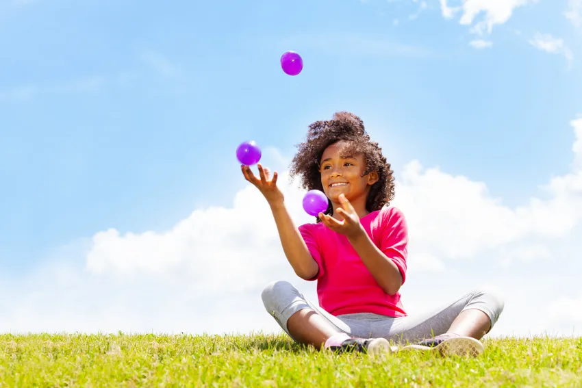 Une enfant découvre la jonglerie avec des balles