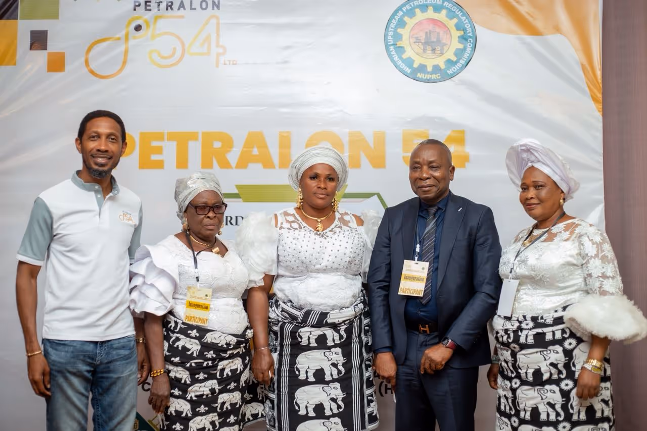 Five people standing in front of a Petralon 54 banner, three women in white lace tops and black-and-white elephant print skirts, one man in a suit, and one man in a white and grey polo shirt with jeans.
