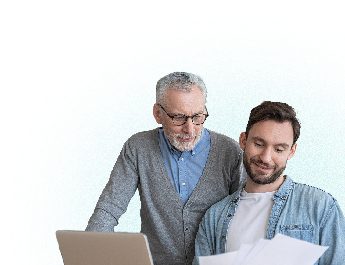 Older man and younger man looking at papers together with a laptop.
