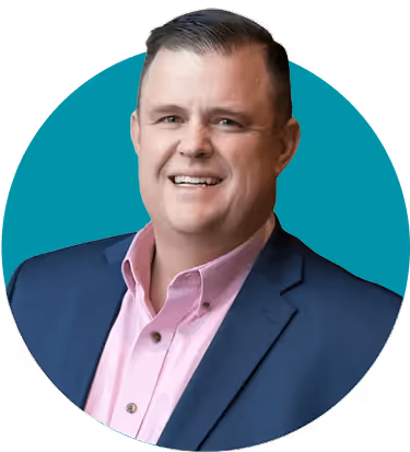 Smiling man wearing a pink shirt and blue blazer with a teal circular background.